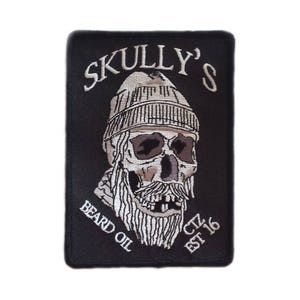Può includere: Toppa ricamata nera con un teschio bianco che indossa un berretto e una lunga barba. Il testo "SKULLY'S BEARD OIL EST. 16" è ricamato in bianco.