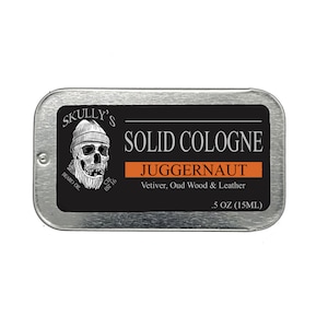 May include: A silver tin with a black label that reads "SKULLY'S SOLID COLOGNE JUGGERNAUT Vetiver, Oud Wood & Leather .5 OZ (15ML)". The label features a skull with a beard and a beanie.