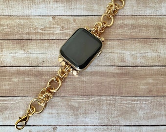 May include: A gold chain watch band with a black watch face. The band is made of interlocking circles and is designed to fit a smart watch.