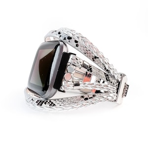 May include: A silver and black smartwatch with a braided leather band. The band has a snakeskin pattern.