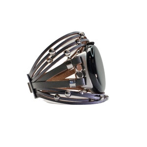 May include: A gray leather watch band with silver studs and a black watch face.
