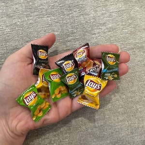 Może przedstawiać: Garść miniaturowych torebek chipsów Lay's w różnych smakach, w tym Classic, Barbecue i Sour Cream & Onion. Torebki są w jasnych kolorach z logo Lay's i opisami smaków. Widoczny jest również napis Party Size.
