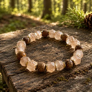 May include: A beaded bracelet featuring alternating clear, faceted, translucent beads and round, tan, speckled wooden beads. The beads are separated by small, thin, gold-toned metal spacers, creating a circular pattern of light and dark textures.