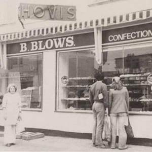 K&ouml;nnte beinhalten: Ein Schwarzwei&szlig;foto eines Ladengesch&auml;fts mit dem Text "B. BLOWS. BAKERS CONFECTIONERS" &uuml;ber den Fenstern. Vor dem Laden stehen Personen.