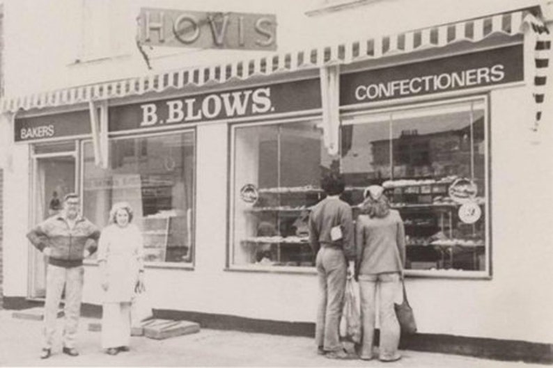 K&ouml;nnte beinhalten: Ein Schwarzwei&szlig;foto eines Ladengesch&auml;fts mit dem Text "B. BLOWS. BAKERS CONFECTIONERS" &uuml;ber den Fenstern. Vor dem Laden stehen Personen.