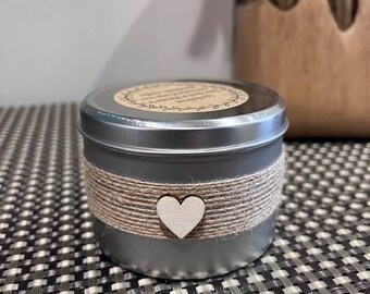 May include: A small silver tin candle with a burlap ribbon and a wooden heart. The candle has a label that says "Handmade with Love".