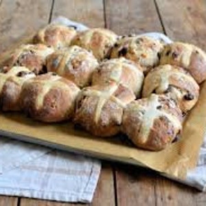 K&ouml;nnte beinhalten: Ein Backblech gef&uuml;llt mit frisch gebackenen Hefezopfbr&ouml;tchen. Die Br&ouml;tchen sind goldbraun und haben ein wei&szlig;es Kreuz auf der Oberseite. Sie sind in einem ordentlichen Muster auf dem Backblech angeordnet.