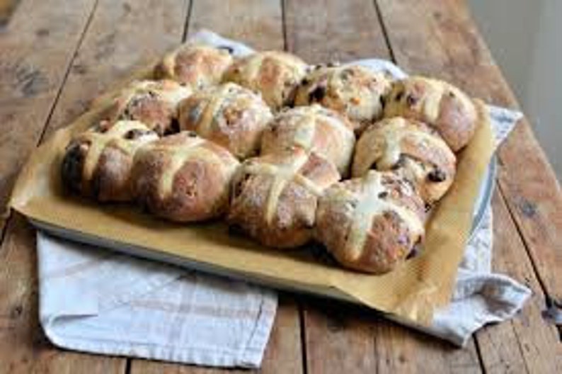 K&ouml;nnte beinhalten: Ein Backblech gef&uuml;llt mit frisch gebackenen Hefezopfbr&ouml;tchen. Die Br&ouml;tchen sind goldbraun und haben ein wei&szlig;es Kreuz auf der Oberseite. Sie sind in einem ordentlichen Muster auf dem Backblech angeordnet.
