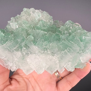 May include: A large cluster of green and clear fluorite crystals. The crystals are stacked on top of each other, forming a large, irregular shape. The crystals are translucent and have a glassy luster.