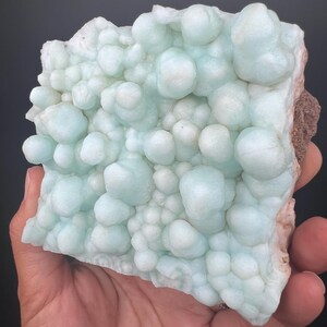 Op de afbeelding: Een groot, lichtblauw, bubbelvormig mineraalspecimen met een ruw, getextureerd oppervlak.