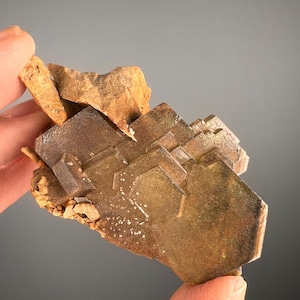 Può includere: Un gruppo di cristalli di barite marroni con una struttura geometrica a strati. I cristalli sono disposti in una formazione impilata, creando una visualizzazione unica e visivamente accattivante.