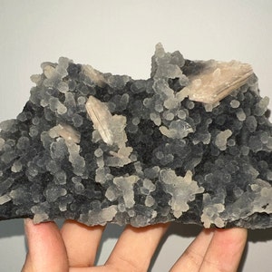 May include: A black and white agate geode with clear quartz crystals and a few larger, translucent, light brown crystals.