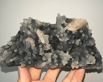 May include: A black and white agate geode with clear quartz crystals and a few larger, translucent, light brown crystals.