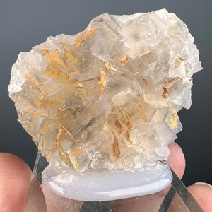 May include: A cluster of clear, faceted crystals with a golden hue. The crystals are arranged in a random pattern and have a rough, natural texture.