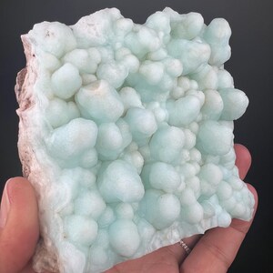 Op de afbeelding: Een groot, lichtblauw en wit, bubbelig mineraalmonster. Het monster heeft een ruw, getextureerd oppervlak.