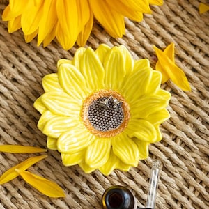 Könnte beinhalten: Eine gelbe Keramik-Sonnenblumenschale mit braunem Zentrum. Die Schale ist perfekt für die Aufbewahrung von Schmuck oder anderen kleinen Gegenständen.