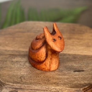 Könnte beinhalten: Kleine Holzfigur einer Schnecke mit glatter, polierter Oberfläche. Die Schnecke ist aus hellbraunem Holz geschnitzt, mit sichtbaren Maserungsmustern. Sie hat einen runden Körper und einen kleinen Kopf mit zwei Fühlern. Die Figur steht auf einer Holzoberfläche.