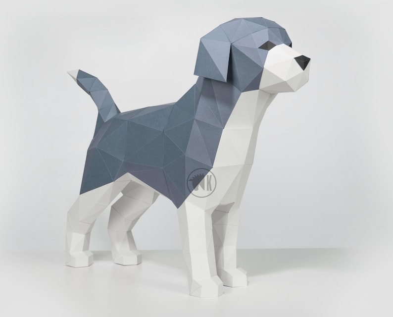 May include: A papercraft model of a dog, made of white and gray paper. The dog is standing on a white surface.