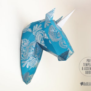 May include: A blue and silver patterned papercraft unicorn head wall decor. The unicorn has a white horn and is made of folded paper. PDF Template & Assembly Guide.