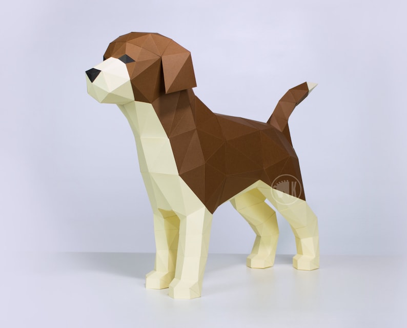 May include: A brown and white papercraft model of a beagle dog. The dog is standing on a white surface and is looking to the left. The model is made of folded paper and has a realistic appearance.