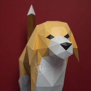 May include: A papercraft model of a beagle dog. The dog is made of white, brown, and black paper and has a realistic appearance. The dog is standing on a red background.