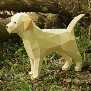 May include: A papercraft model of a yellow Labrador Retriever dog standing in a forest setting. The dog is made of folded paper and has a realistic appearance.