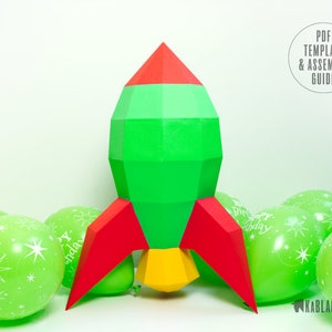 May include: A green, red and yellow paper rocket with a red and yellow flame. The rocket is surrounded by green balloons with white stars and the text "Happy Birthday".