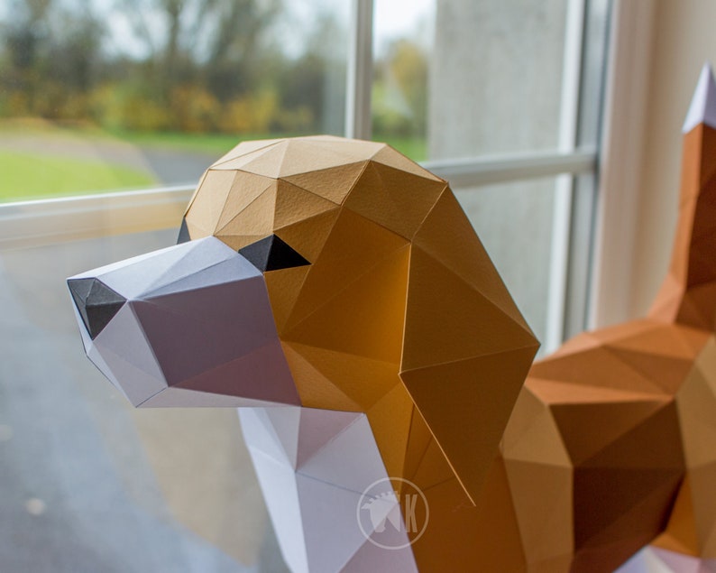 May include: A papercraft model of a beagle dog, made from brown, white, and black paper. The dog is posed with its head turned to the side, looking towards the viewer. The model is partially assembled, with some of the paper pieces still attached.