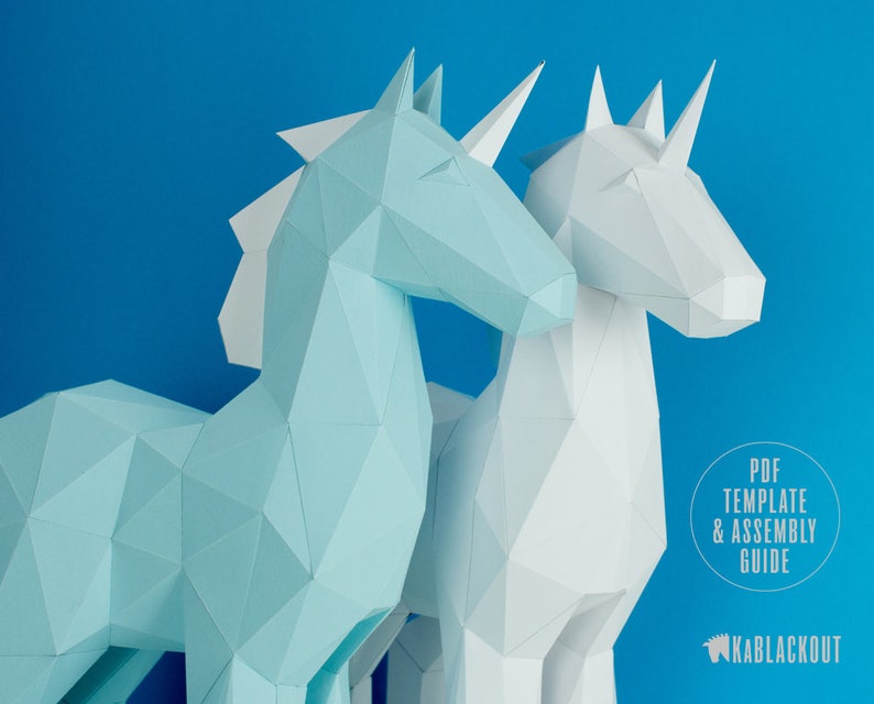 May include: Two papercraft unicorn models, one light blue and one white, against a bright blue background. The text "PDF TEMPLATE & ASSEMBLY GUIDE" is visible in the lower right corner, along with the logo "KABBLACKOUT".