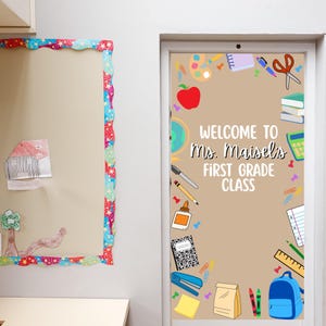 May include: A classroom door decorated with school supplies and the text "Welcome to Ms. Maisel's First Grade Class." A bulletin board with a colorful border and a child's drawing is to the left.