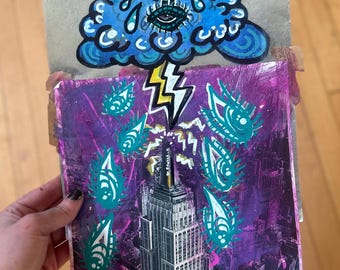 May include: A mixed media artwork featuring a blue cloud with multiple eyes and a lightning bolt striking a skyscraper. The background is a purple cityscape with more eyes raining down.