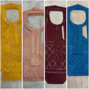 May include: Four embroidered tunic tops in gold, pink, burgundy, and blue. Each tunic features intricate geometric and knotwork designs around the neckline and front panel. The tunics are displayed vertically, showcasing the detailed craftsmanship.