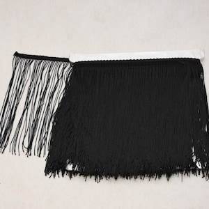 May include: Black fringe trim with a smooth, woven texture. The fringe is approximately 1 inch (2.5 cm) long.