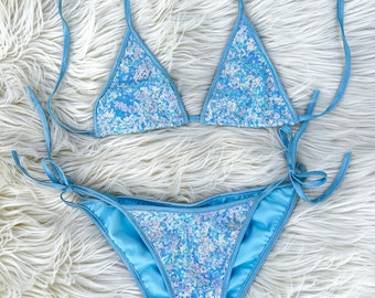 May include: A light blue bikini with a sequined top and bottom. The bikini is made of a soft, stretchy fabric and has adjustable straps.
