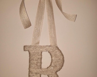 May include: A brown burlap letter R with white fabric flowers and a brown satin ribbon bow.