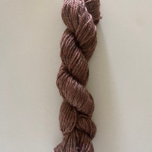 May include: A skein of brown yarn, twisted and ready for knitting or crocheting.