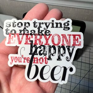 May include: A white sticker with black and red text that reads "stop trying to make everyone happy you're not beer".