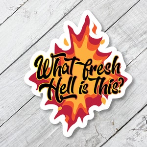 May include: A sticker with a fiery orange and red design. The text "What fresh hell is this?" is written in black cursive lettering.