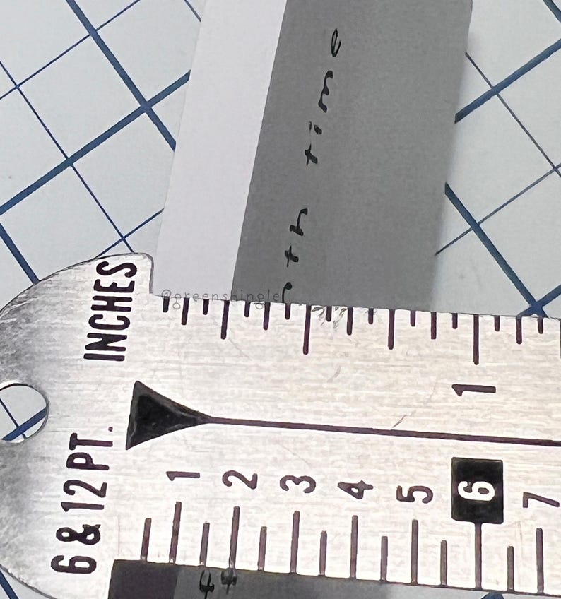 May include: A close-up of a metal ruler with markings in inches. The ruler is marked with numbers from 1 to 7. The text "6 & 12 PT. INCHES" is printed on the ruler.