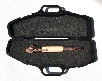 May include: A handcrafted pen with a light wood barrel and copper-colored metal accents, displayed in an open black case with foam padding. The pen features intricate detailing on the metal components, including the tip and the end cap.