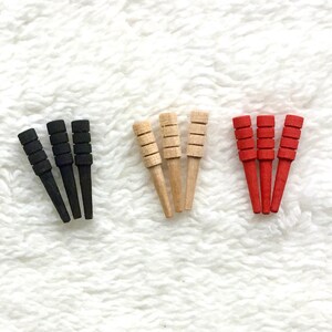May include: Three sets of four wooden dowels, each set in a different color: black, natural wood, and red.