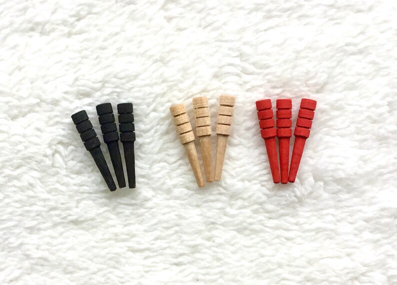 May include: Three sets of four wooden dowels, each set in a different color: black, natural wood, and red.