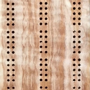 May include: A wooden cribbage board with a light brown stain. The board has two sets of holes for pegs, a start area, and two scoring areas. The board is made of wood with a natural grain pattern.