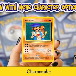 May include: A yellow "The Graduate" Pok&eacute;mon card featuring an illustration of a graduate with a Charmander. The card has text that reads "2026 HP" and "Diploma!" The card is held in a hand with black nail polish. The text "Charmander" is at the bottom.