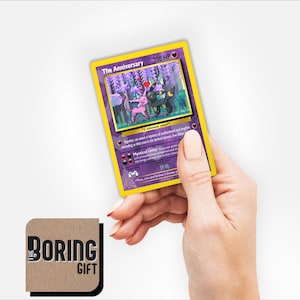 May include: A purple and yellow Pokemon card with a picture of two Pokemon, one pink and one black, with the text "The Anniversary" and "200 HP".