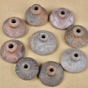 Puede incluir: Nueve hileras de cer&aacute;mica de terracota con intrincados dise&ntilde;os geom&eacute;tricos. Las hileras son circulares con un agujero central y varios patrones tallados en la superficie.