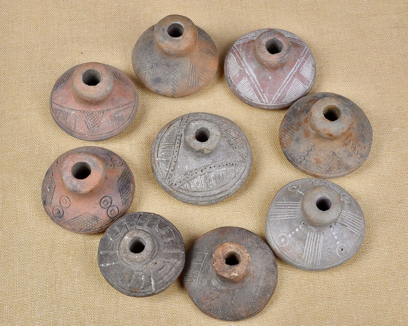 Puede incluir: Nueve hileras de cer&aacute;mica de terracota con intrincados dise&ntilde;os geom&eacute;tricos. Las hileras son circulares con un agujero central y varios patrones tallados en la superficie.