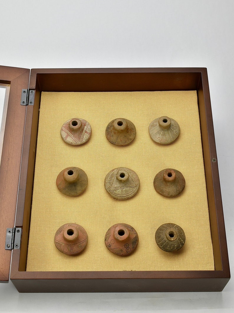 Clay spindle whorls being displayed in a wooden case.