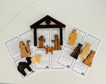May include: Wooden nativity set with figures of Mary, Joseph, Jesus, a shepherd, a wise man, an angel, a camel, and a sheep. The set also includes a wooden stable and scripture cards.