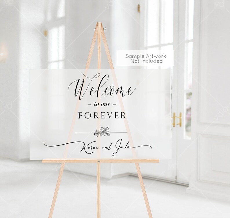 以下が含まれることがあります： 「Welcome - to our - FOREVER Karen and Jack」と黒の書体で書かれた白いウェルカムサイン。サインは木製イーゼルの上に置かれています。